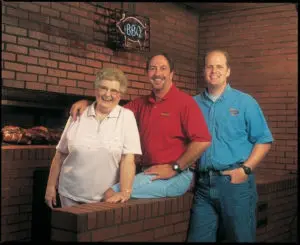 Three people posing in a restaurant kitchen