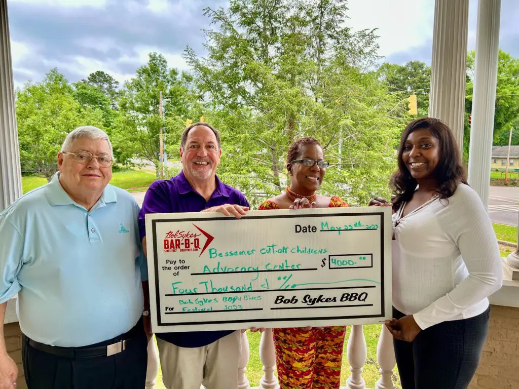 Four people posing with a big, life-size check